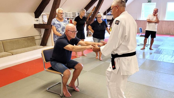 Seisin-instruktören Christer Johansson ger Maths Frid och de andra medlemmarna från PRO Snöstorp/Vallås tips om hur man på enklast, tryggast och minst kraftödande sätt hjälper en person upp från en stol. Foto: Rickard Gustafsson