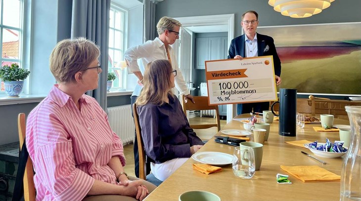 Laholms Sparbanks VD Dennis Davidsson tackar majblommeföreningarna för insatserna och visar checken på 100 000 kronor. Foto: Johan Jönsson